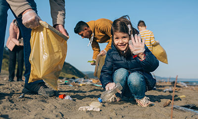 Young girl picking up rubbish on the beach in the summer